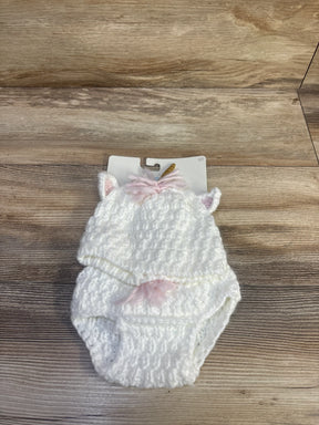 Top-down view of white crocheted unicorn baby hat and matching diaper cover showcasing ear details, pink yarn mane and small gold horn on light wood background
