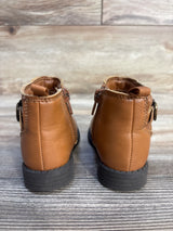 Back view of brown toddler ankle boots with zippers, rubber soles on wood floor