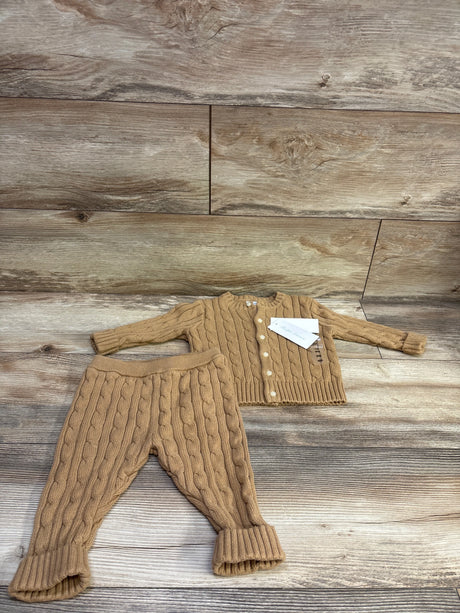 Flat lay of a Ralph Lauren two-piece cable knit cardigan sweater and pants set in tan with a wood plank background