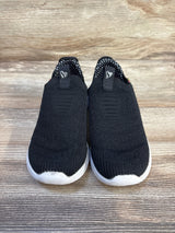 Black slip-on kids sneakers with white soles on wood background, gently used children's shoes