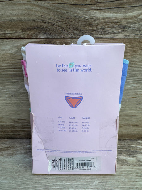Rear view of 5-pack seamless bikinis packaging showing size M 7/8 sticker, size chart, and pink box against wood background