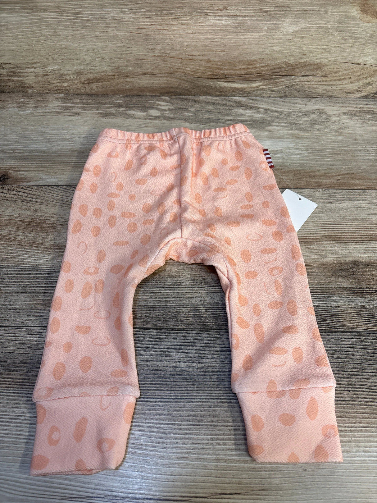 Peach baby pants with polka dot pattern displayed on wood background