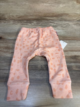Peach baby pants with polka dot pattern displayed on wood background