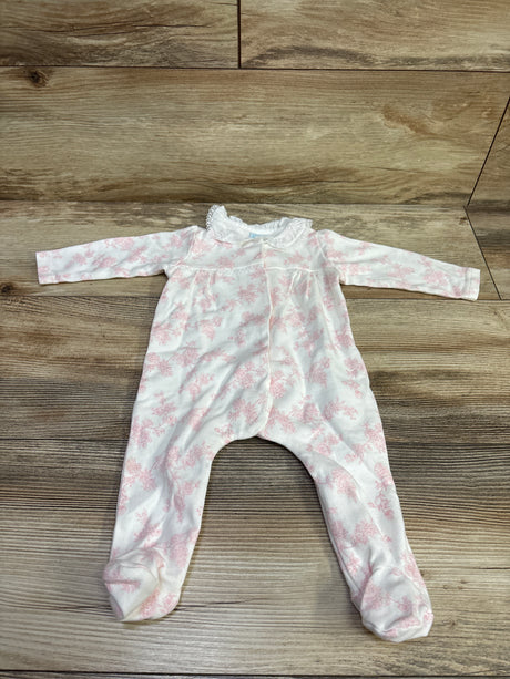 Top-down view of white footed coverall with pink floral pattern and ruffled collar on a wood surface