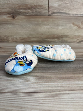 Cute baby slippers with cartoon blue dog and word Hooray on soft fabric on wooden surface