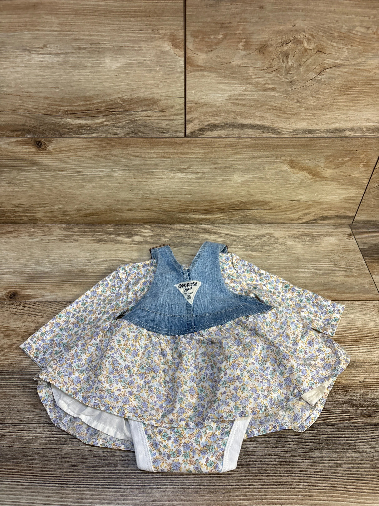 Baby dress with denim top and floral skirt, long sleeves, matching bloomers on wood floor