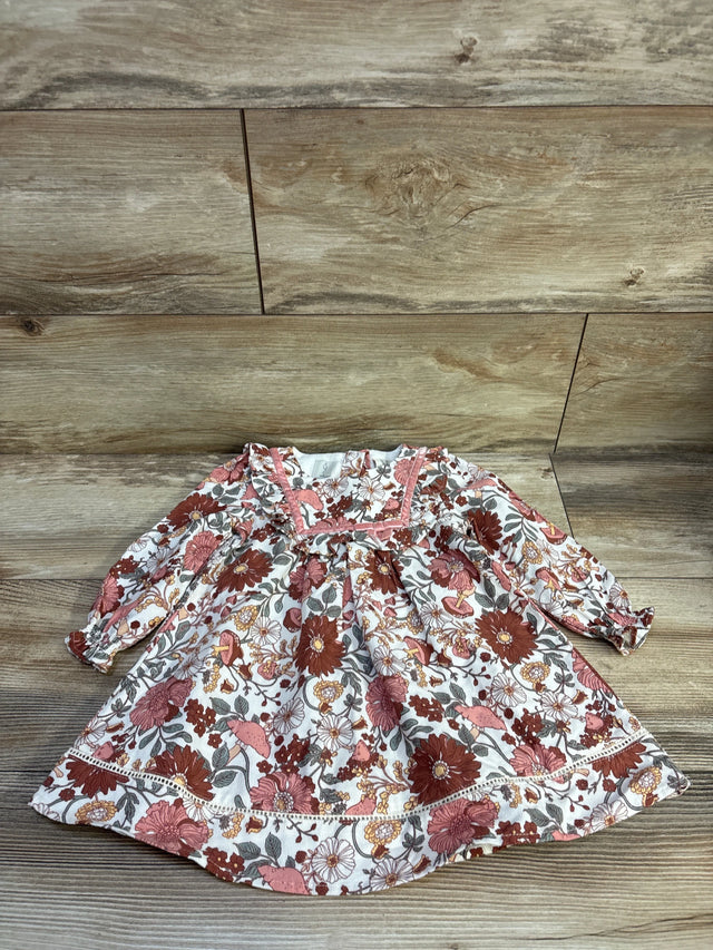 Front view of the Joie ivory floral long sleeve dress showcasing pink trim and flared skirt on a wood plank background