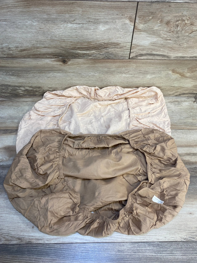 Two neutral fitted crib sheets with elastic edges on wood floor, baby bedding essentials