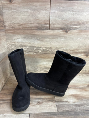 Black suede kids winter boots with faux fur lining on wood floor background