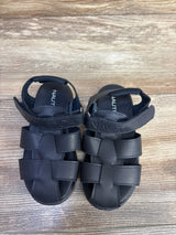 Top down view of Nautica toddler navy fisherman sandals showcasing woven straps and Velcro ankle strap with Nautica logo on wood floor