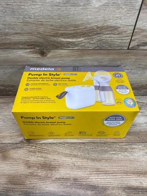 Angled front view of Medela Pump In Style double electric breast pump box showing motor unit and two bottles on wood background