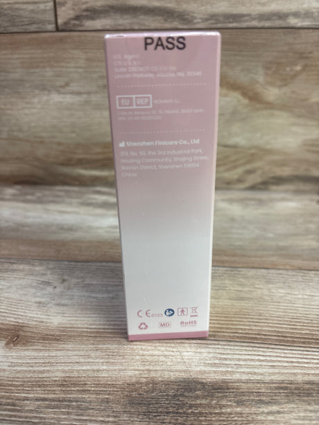 Rear view of NEW SUWU No-Touch Infrared Thermometer pink packaging showing PASS label on a wood surface