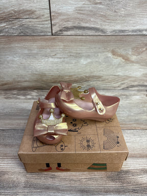 Pink toddler dress shoes with gold crown and bow, placed on a decorative shoebox