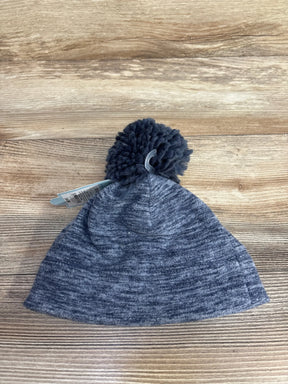Grey knit winter beanie hat with large pom pom on wooden background