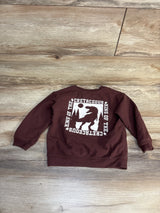 Flat lay of Cat & Jack 68 Million Years Ago Dino Sweatshirt Brown sz 3T showcasing King of the Cretaceous T-Rex graphic on wood plank floor