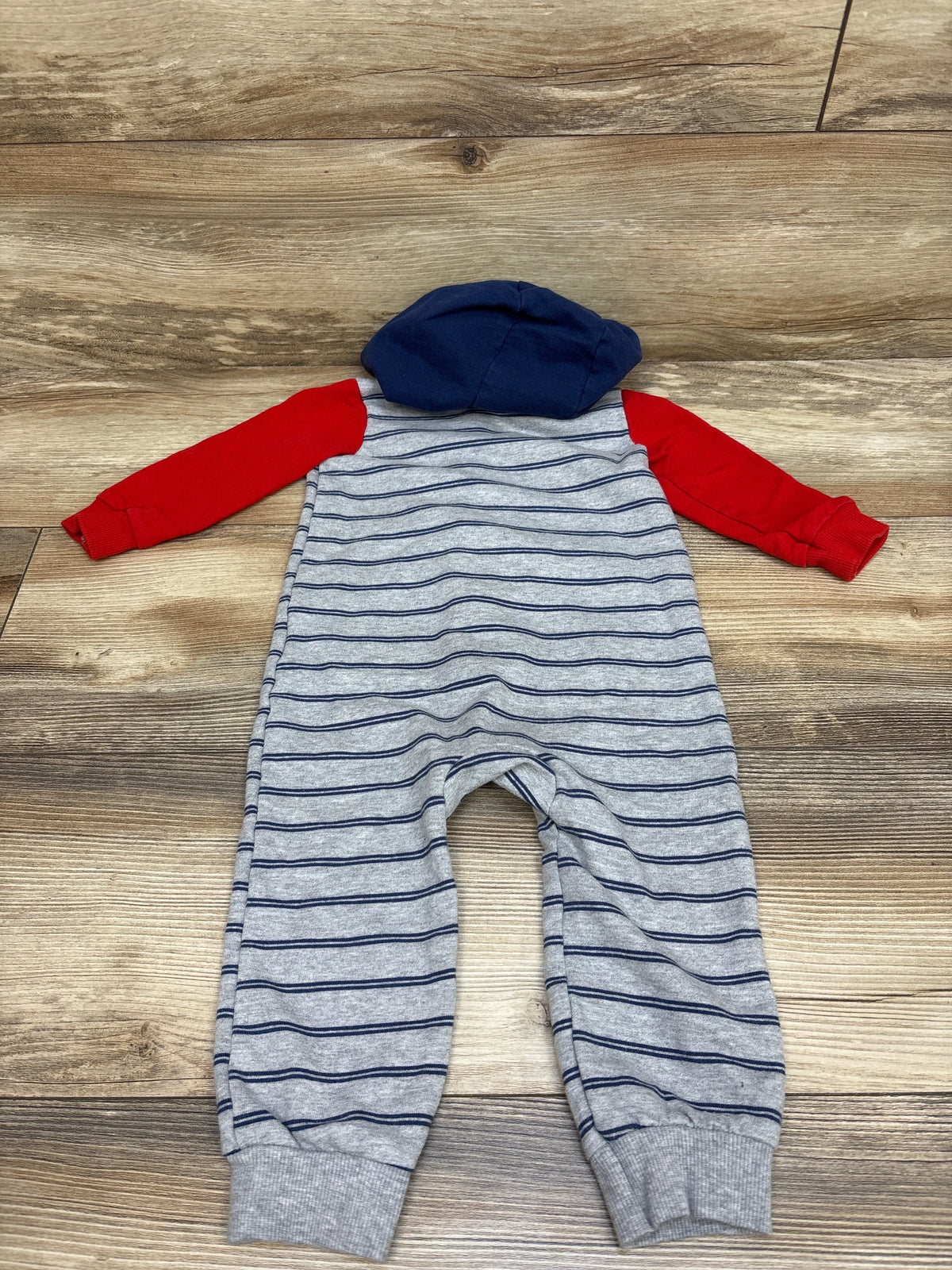 Front view of Carter’s gray hooded coverall, size 18 months, with navy stripes, red sleeves, and navy hood on wood