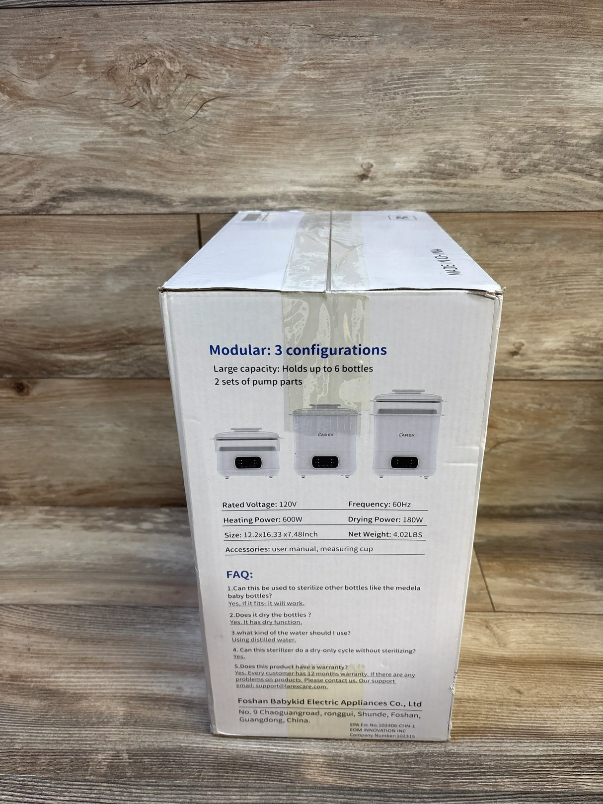 White box for baby bottle sterilizer with product specifications and FAQ on wood background