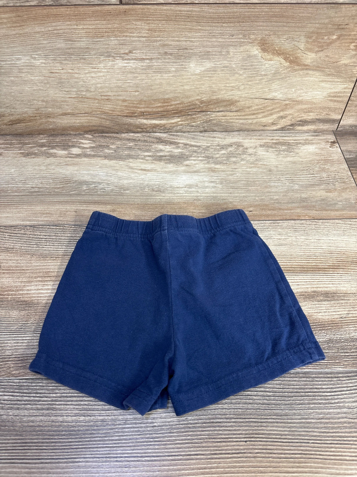 Flat lay of navy Carter's toddler bike shorts size 3T showing elastic waistband and short inseam on wood background