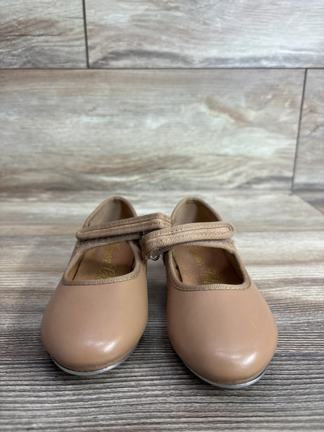Front view of tan toddler tap shoes showcasing Mary Jane velcro strap and metal toe taps with wood plank background