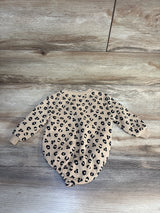 Beige baby onesie with black leopard print, long sleeves, laid on wood floor