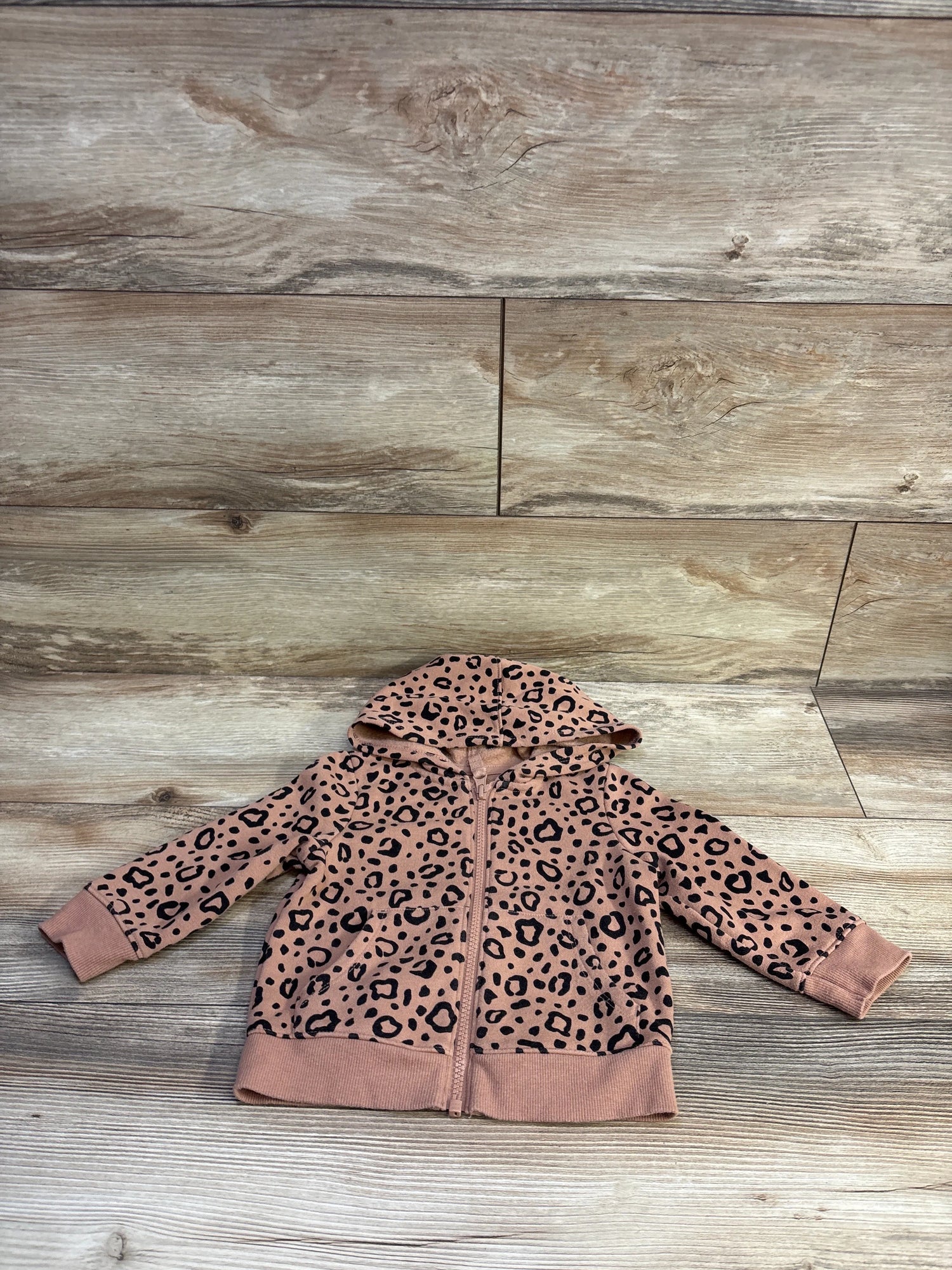 Flat lay of Cat and Jack toddler full-zip leopard print hooded jacket showing zipper and cuff details on light wood background size 12 months