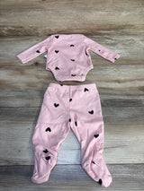 Pink baby outfit set with long sleeve onesie and footed pants, black heart print, on wood background