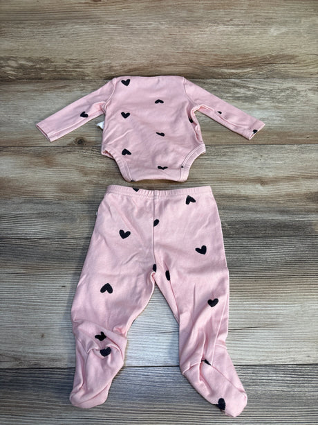 Pink baby outfit set with long sleeve onesie and footed pants, black heart print, on wood background