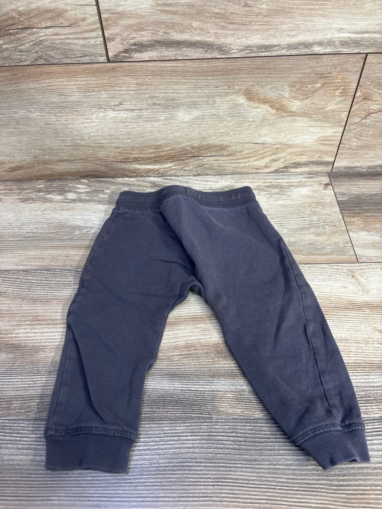 Flat lay of H&M grey baby joggers (9-12 months) showing elastic waistband and ribbed ankle cuffs on wood background