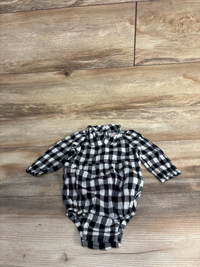 Black and white checkered long-sleeve baby romper with gathered waist on wooden floor