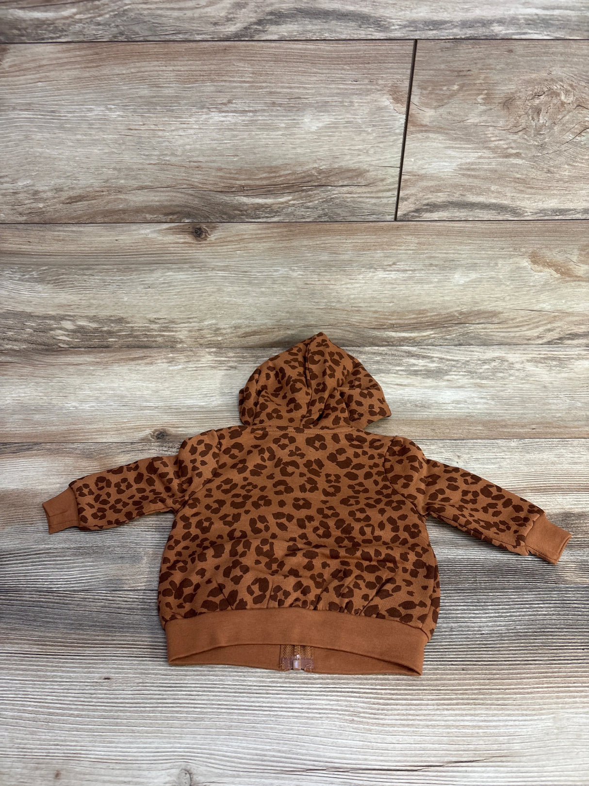 Back view of brown toddler hoodie with dark leopard print pattern on wooden floor