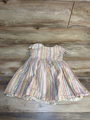 Front view of pastel striped short-sleeve baby dress showcasing pink yellow blue and cream vertical stripes with smocked bodice on wood plank floor
