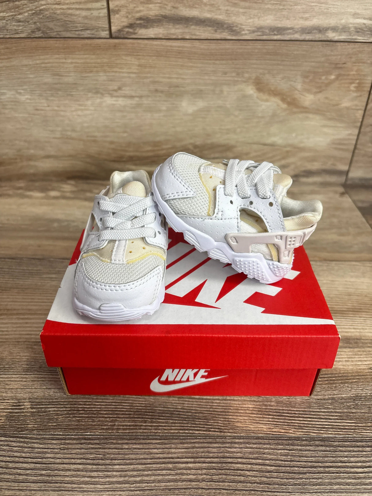 Front three quarter view of Nike Air Huarache Run TD toddler white sneakers showing mesh and leather upper, heel strap on red Nike box