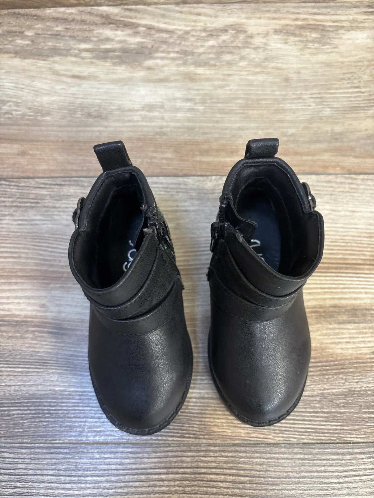 Black toddler boots with side zippers and pull tabs, kids footwear on wood floor