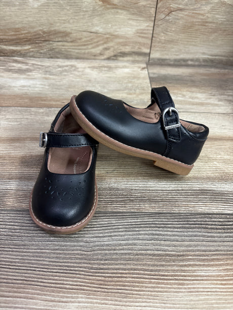 Top and side views of black Stride Rite Mara Mary Jane flats with buckle straps and perforated toes on a wood-look surface