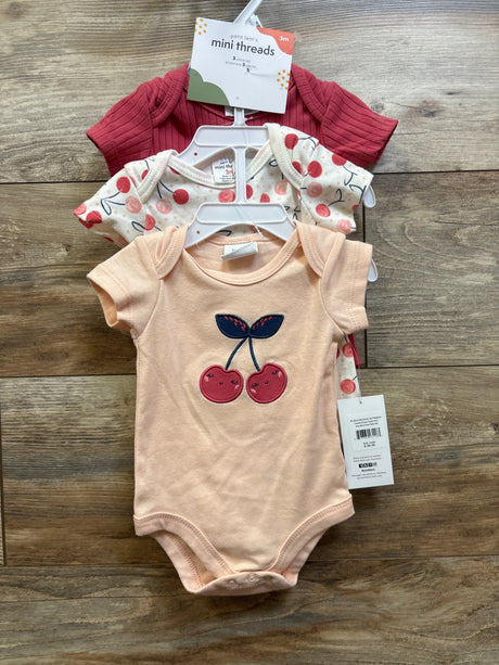 Front view of Petit Lem Mini Threads three piece bodysuit set in red, cherry print, and peach on wood grain background