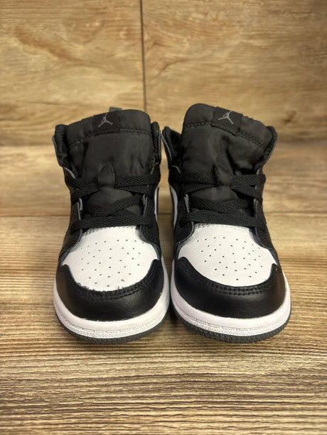 Front view of Air Jordan 1 Mid TD Iron Grey sneakers showcasing black and white color blocking with Jordan logos on a wood surface