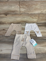 Flat lay of three Disney Baby newborn Bambi pants showing embroidered Bambi faces and tan and white stripes on wood backdrop