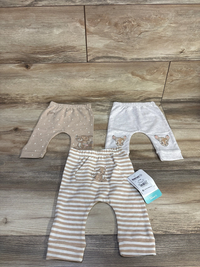 Flat lay of three Disney Baby newborn Bambi pants showing embroidered Bambi faces and tan and white stripes on wood backdrop