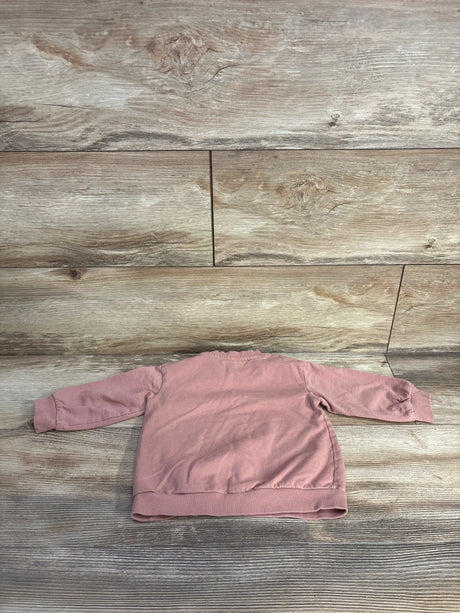 Back view of H&M toddler pullover sweatshirt in pink showing long sleeves and ribbed cuffs and hem on a light wood background