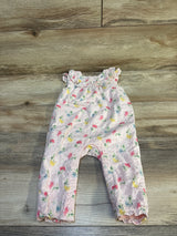 Pink floral baby romper with ruffled shoulders and eyelet fabric on wood background