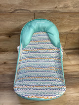 Front view of Summer Deluxe Baby Bather showcasing turquoise padding and multicolored wave pattern with a wood plank background