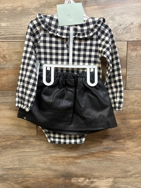 Front view of baby 4-piece layette set showcasing a black-and-white checkered top and black skirt on a wooden background