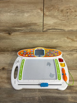 Front of VTech Write and Learn Creative Center with magnetic drawing board, attached stylus, alphabet stamps on wood floor