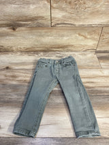 Flat-lay front of toddler green slim denim jeans showing elasticized waist and straight legs on wood background