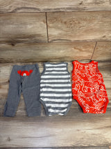 Flat lay of Carter's 3-piece baby set: grey pants with red crab, grey-striped tank, and red crab-print bodysuit on wood