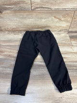 Black kids joggers with elastic waist and cuffs, laid flat on wood floor