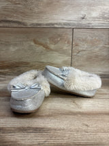 Pair of silver toddler moccasin slippers with faux fur lining and bow on wooden floor