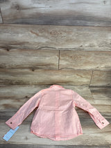 Light pink long sleeve button-up kids shirt laid flat on wood floor