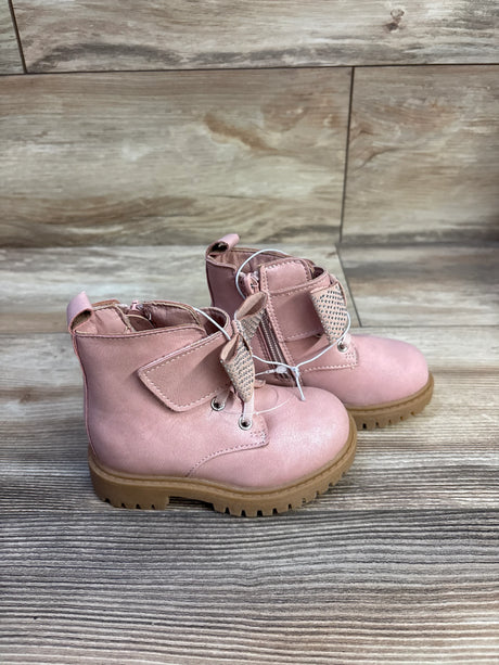 Three-quarter view of Jessica Simpson Daria toddler ankle boots showing rhinestone bow, side zipper and tan lug sole on wood