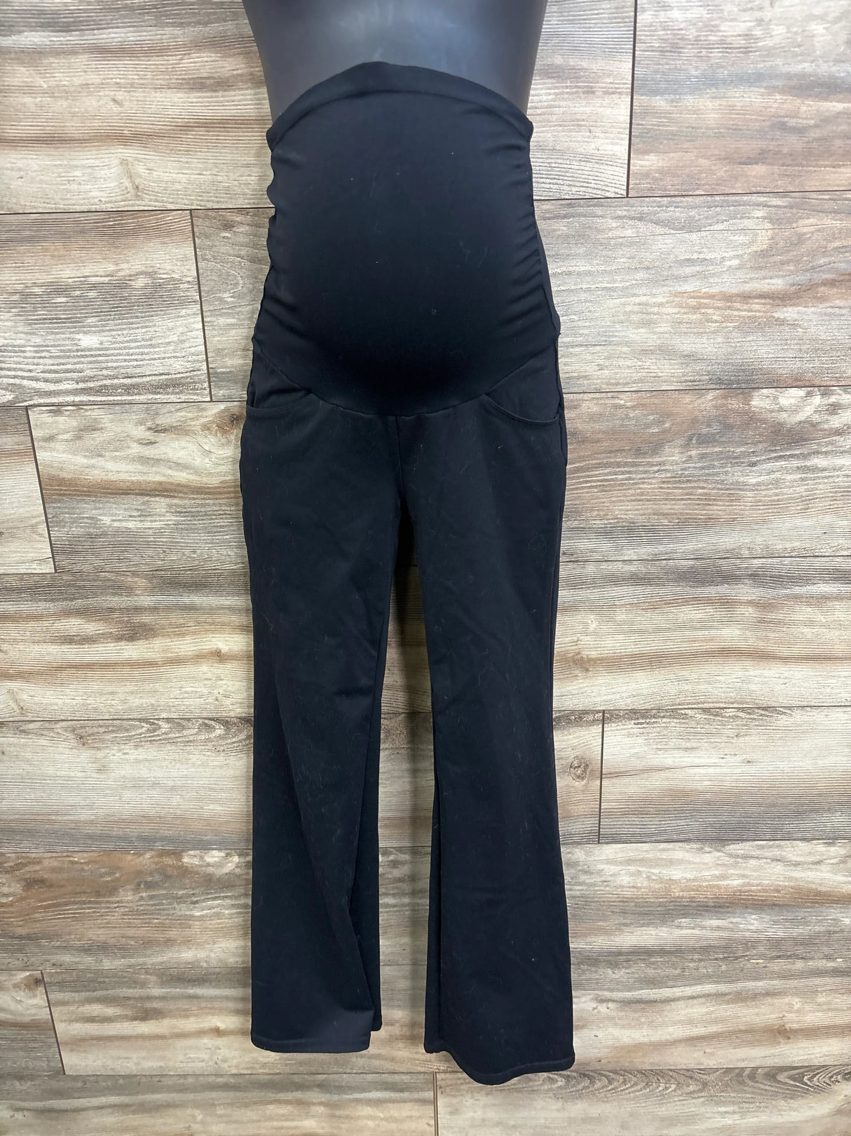 Front view of black Ewedoos maternity over-belly pants showing stretch belly panel and slight flare against wood floor